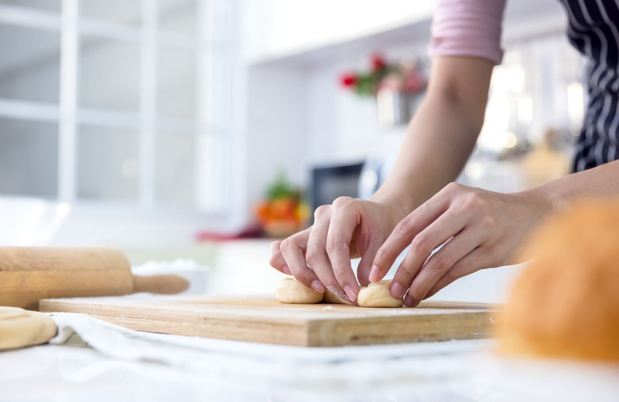 笑顔の若い女性は、キッチンで甘いパイやペストリー生地を作る木製のローラーピンで働く、家族の夕食やデザートベーキングバンズを準備エプロンで調理幸せなミレニアル世代の女性愛妻