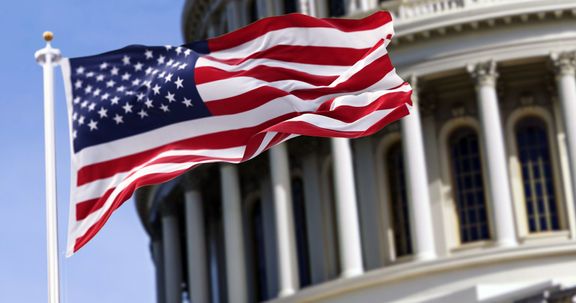 国会議事堂の前を飛ぶアメリカ合衆国の旗が背景にぼやけた