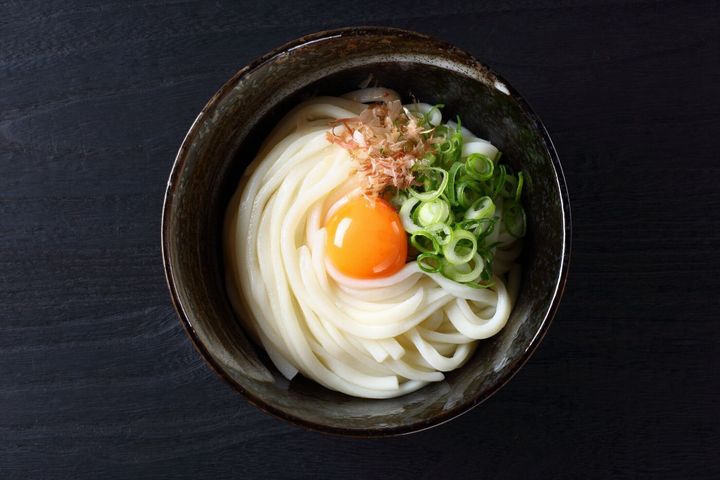 黒いテーブルに生卵を入ったうどうも