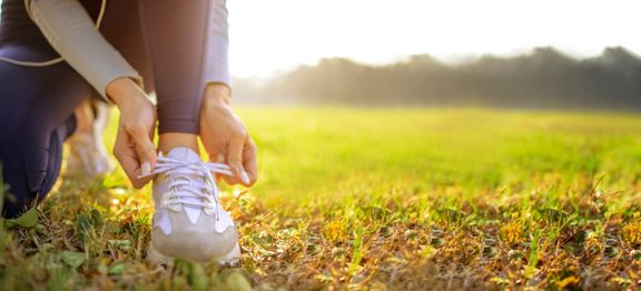 若い女性ランナーは、朝に外でジョギングの準備をしている彼女の靴を結ぶ