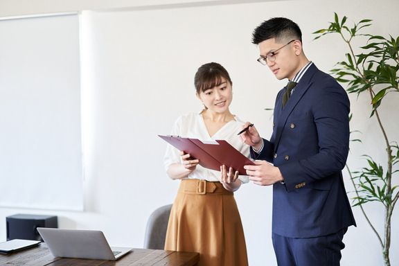 アジアの先輩ビジネスマンに資料のチェックを求めるビジネスウーマン