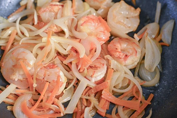 フライパンに入った炒めたえびとにんじんと玉ねぎ