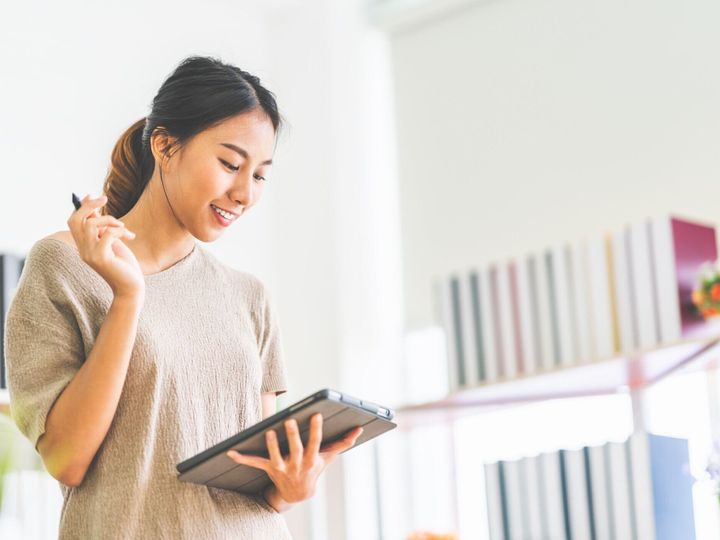 若い美しいアジア女の子はオフィス コピー スペースを持つデジタル タブレットを使用して自宅で作業します。ビジネス オーナー起業家、中小企業スタートアップ企業、またはカジュアルな