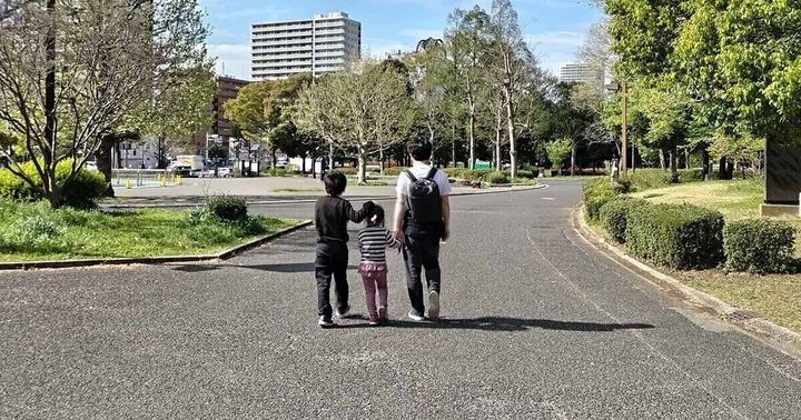 公園を歩く家族の後ろ姿