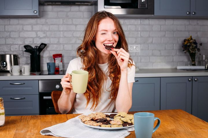 クッキーを食べたり、ミルクを飲んだりする女性。