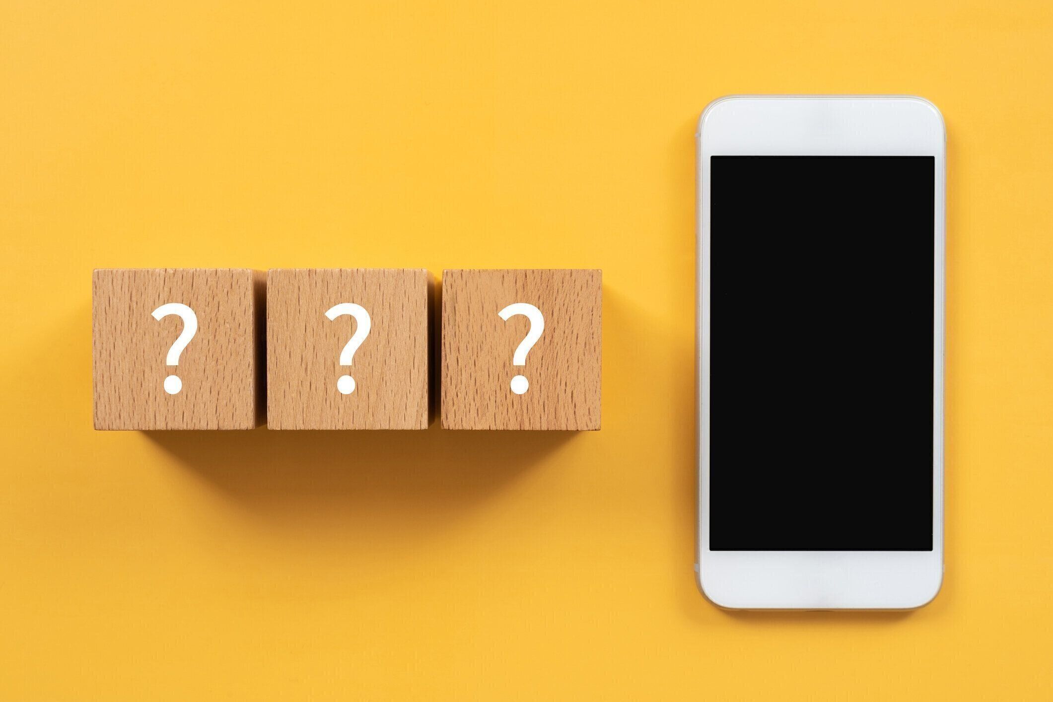 コンセプトの疑問符テキストとスマートフォン付きの木製ブロック。