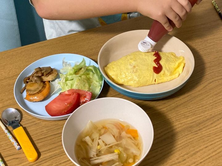 オムライスにケチャップでデコレーションをしている