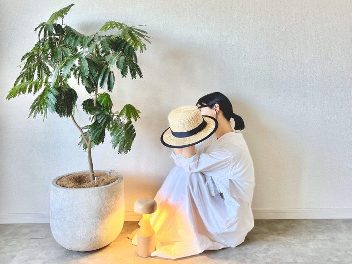 植物と照明と帽子を持った女性