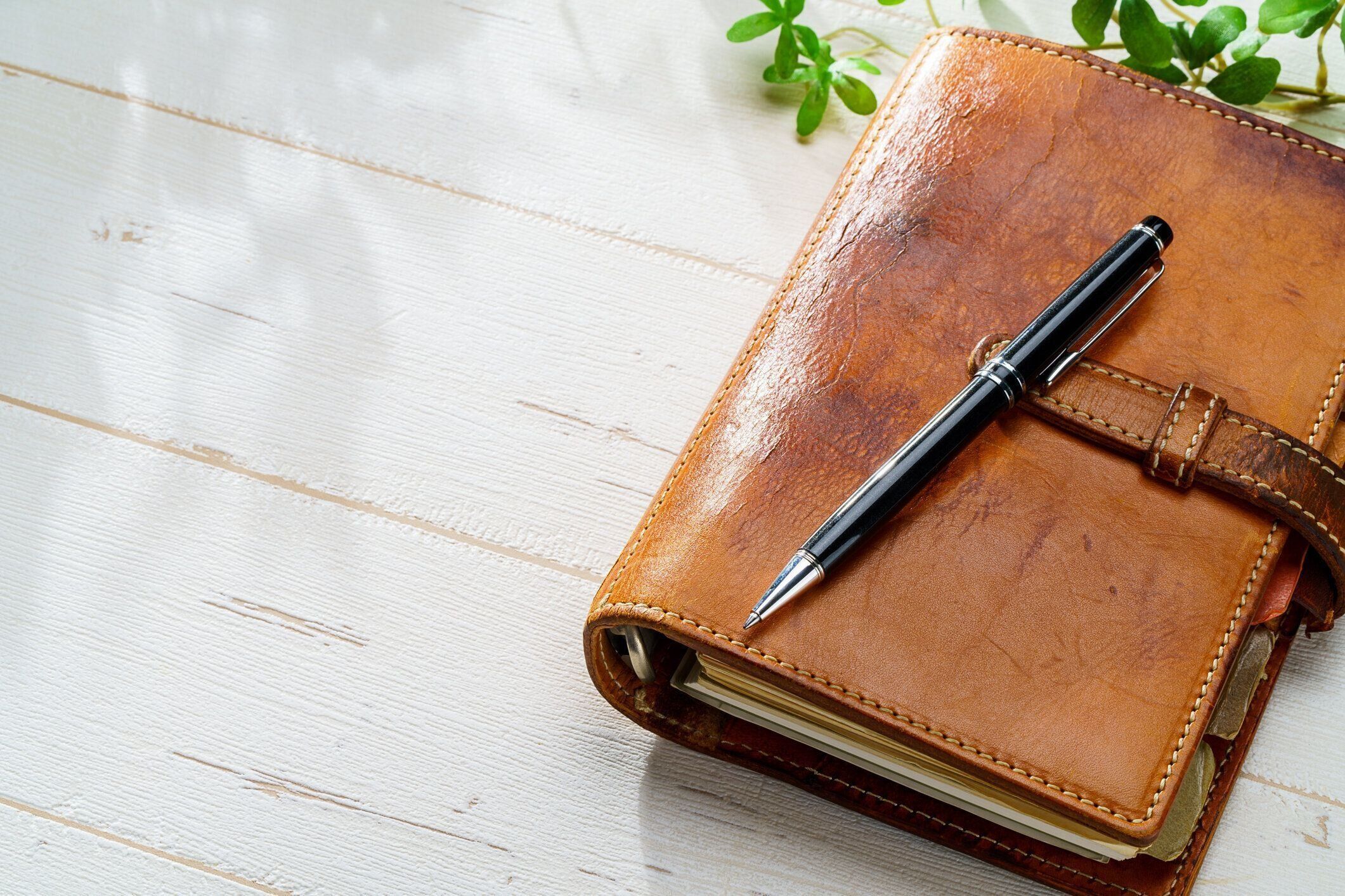 木のテーブルの上のリングバウンドプランナーとペン