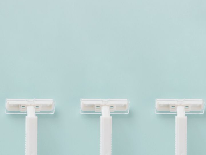 青い背景に使い捨ての白いプラスチックかみそりコピー スペース