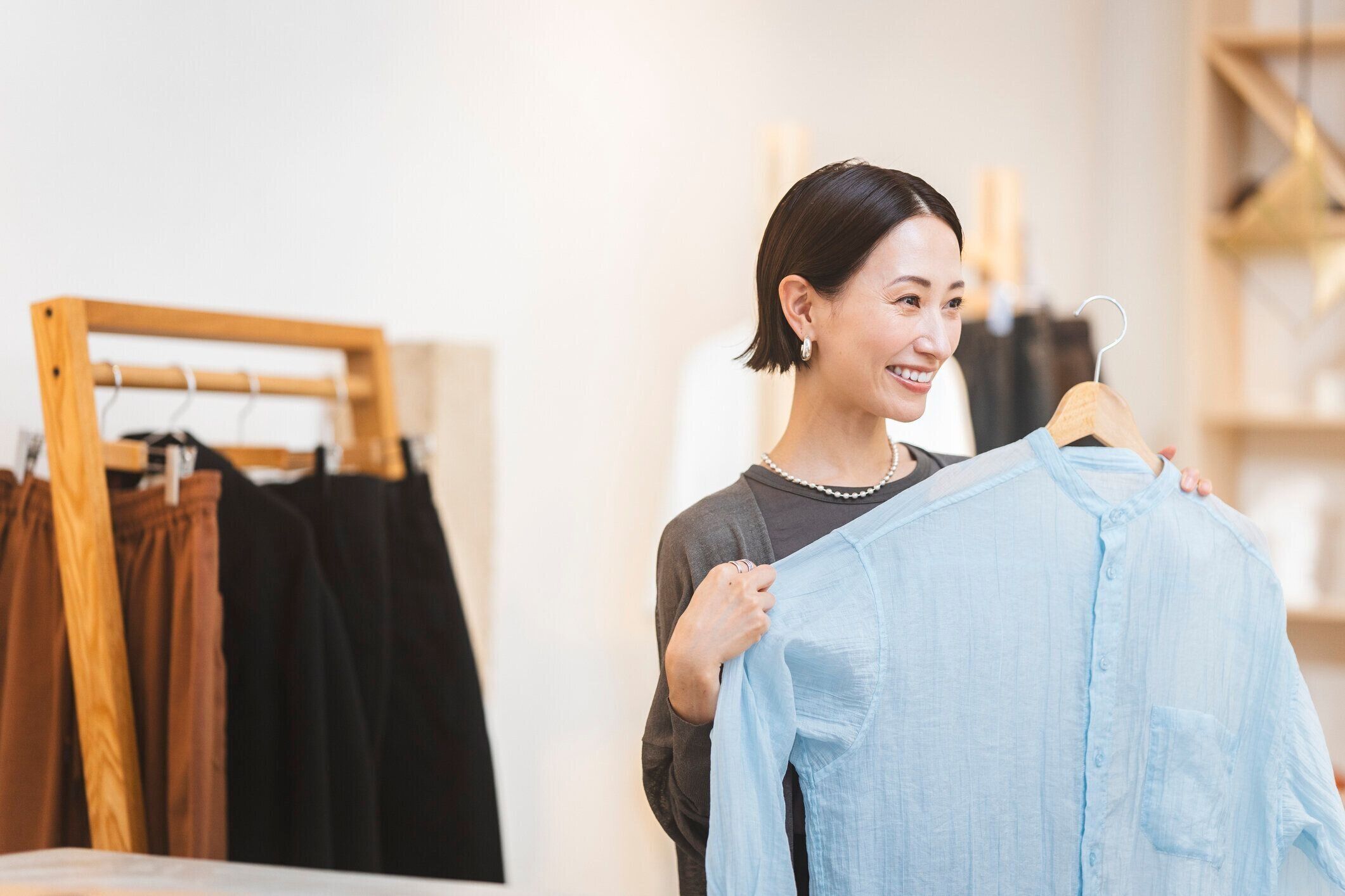 アジア人女性が衣料品店で買い物をしている。