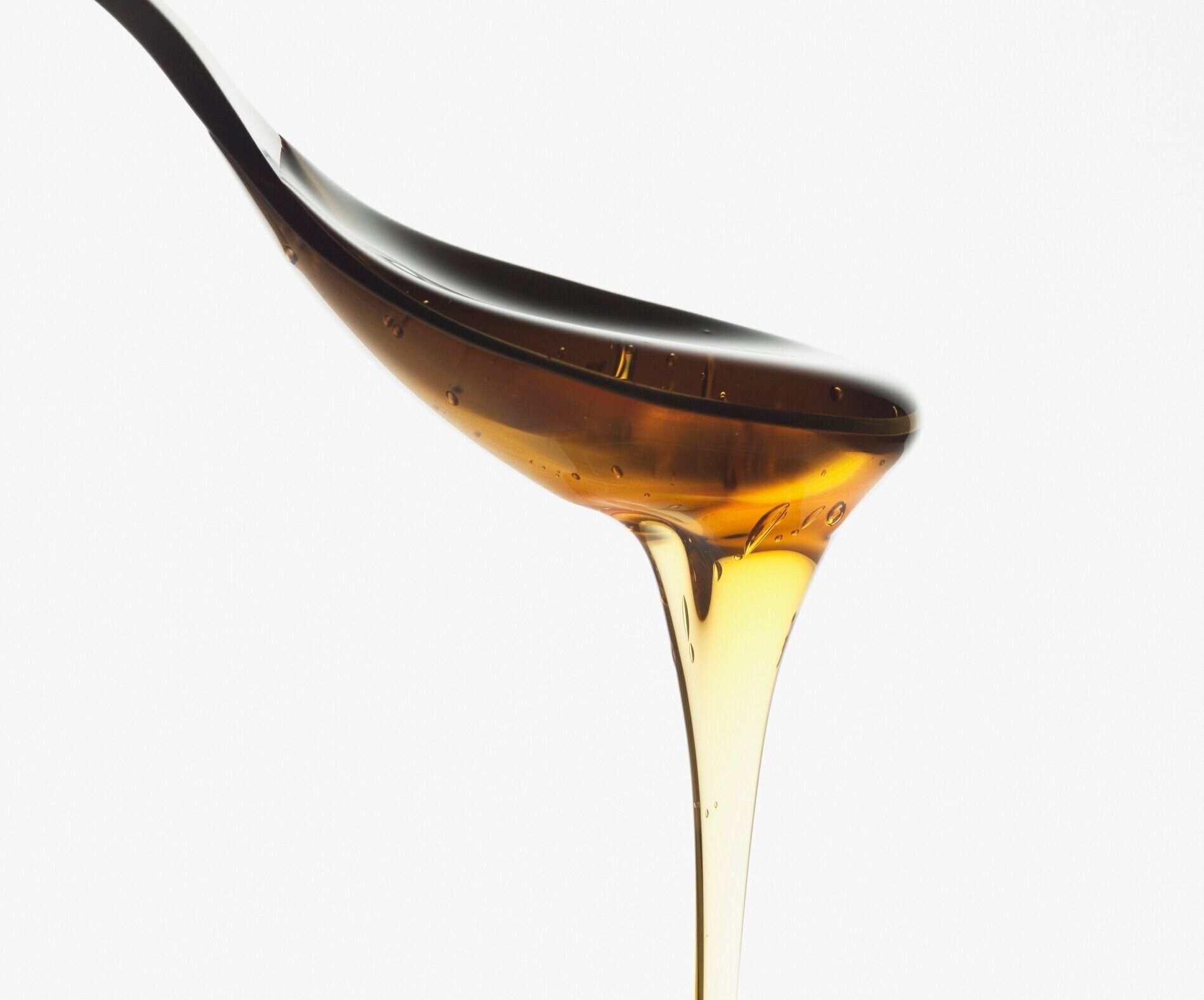 ハチミツのクローズアップのスプーンから水が滴っています。