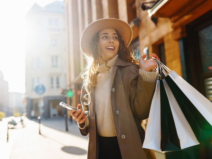 ショッピングバッグを運ぶ秋のエレガントな女性が街の通りを歩いています。