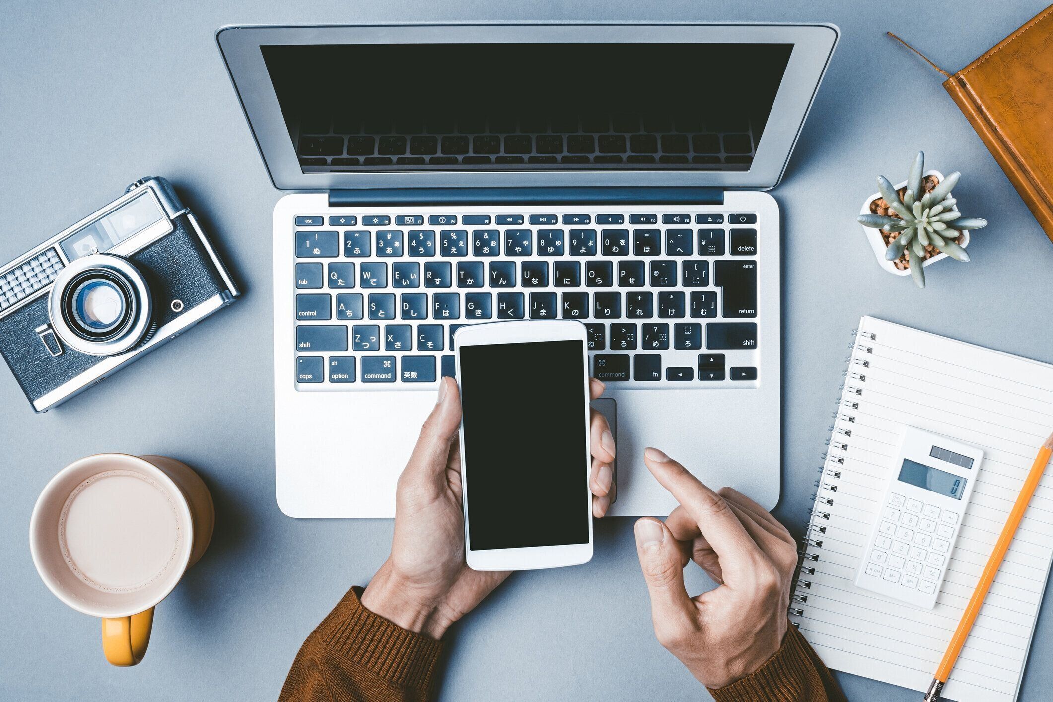 ラップトップとスマートフォンで働く男性