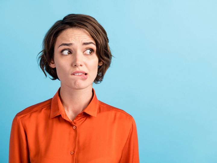 悲しい落ち込んだ不愉快な女性恐ろしい表情のクローズアップ写真は、大きな間違いを感じた大きな間違いは、横の空のスペースの咬傷の唇はオレンジ色のシャツを着て、オレンジ色の背景�