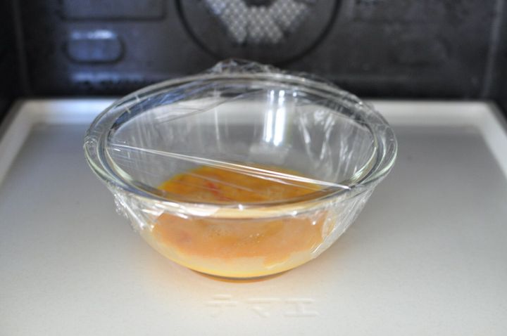 卵を入れたボウルにラップをかけて、レンジで加熱する様子