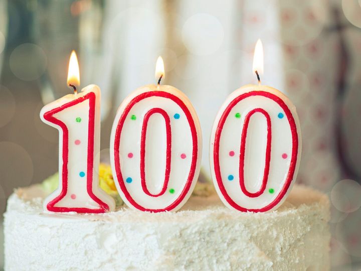 テーブルの上の甘いケーキの上にナンバーワン百、100歳の誕生日として誕生日キャンドル