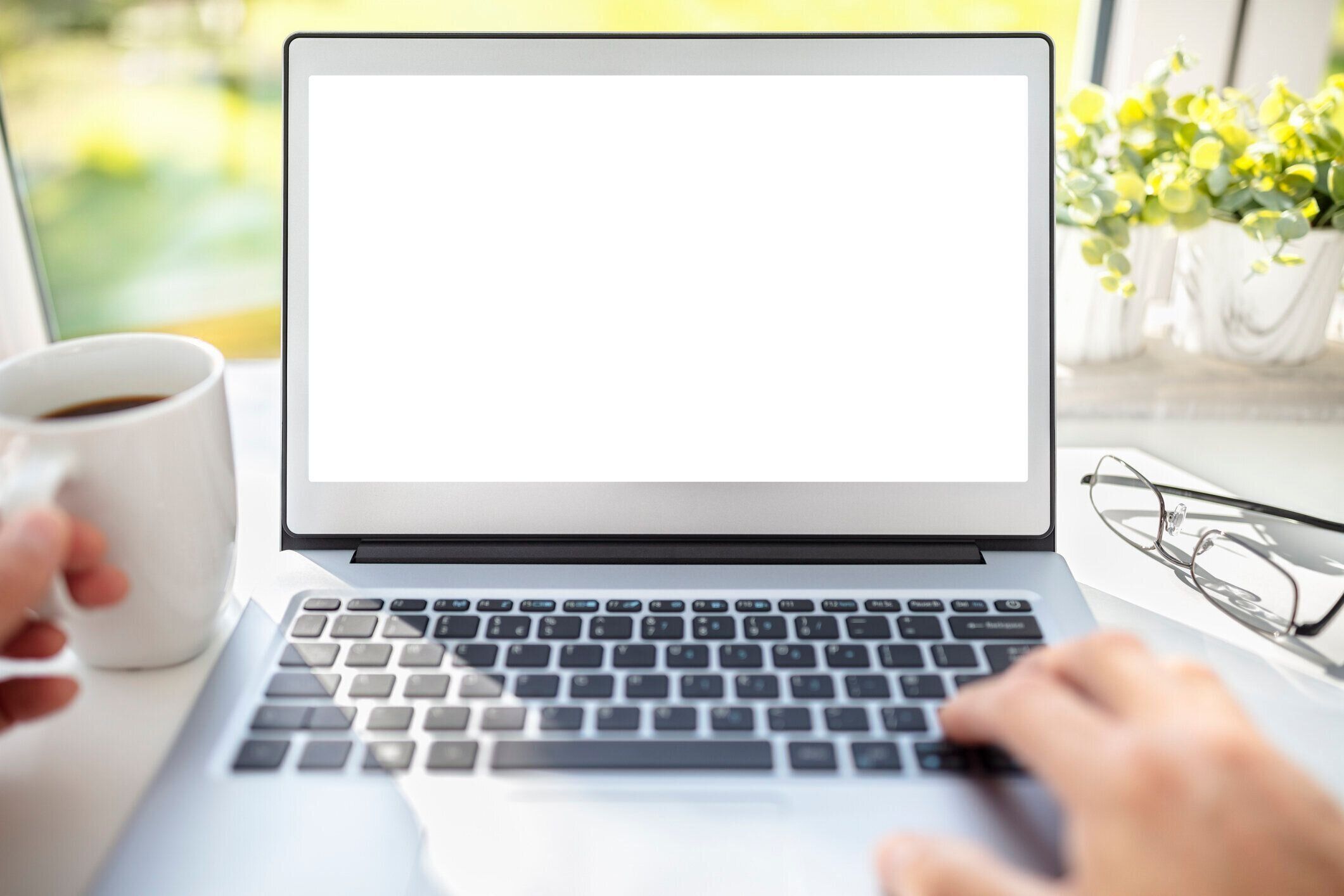 オフィスの机の背景にモックアップ用の空白の画面を持つノートパソコン