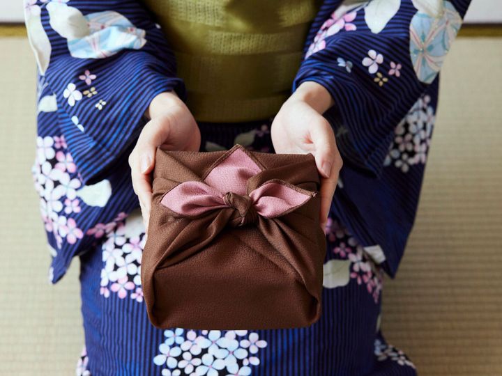 贈り物を示す日本の服を着た女性の手