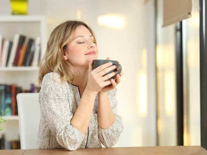 家でコーヒーのマグカップを保持して呼吸の女性