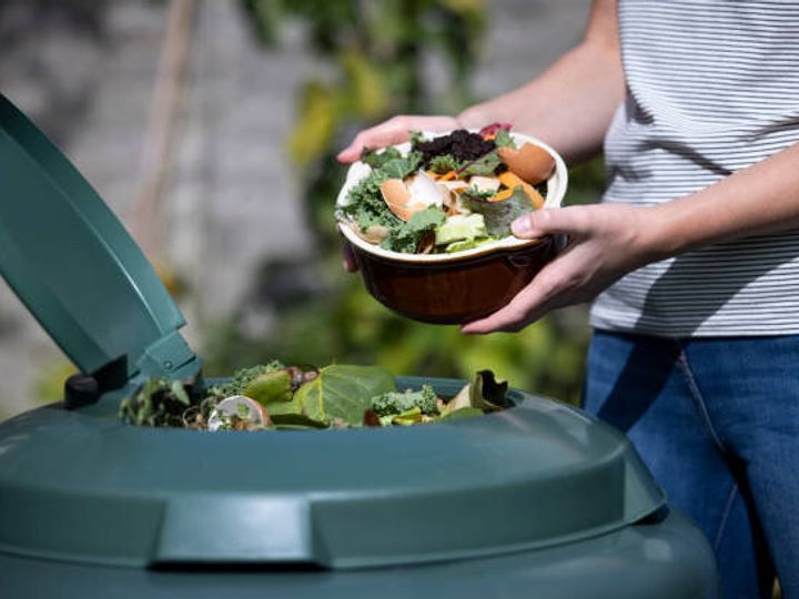 自宅で庭の堆肥に食品廃棄物を空にする女性のクローズアップ