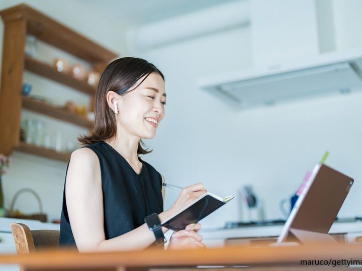 パソコンを見ながらメモをする女性