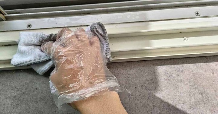 窓のサッシを拭いている