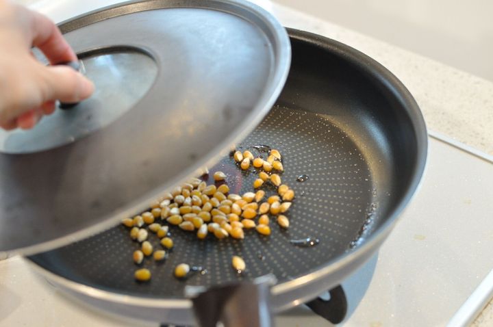 ポップコーンを入れたフライパンに蓋をする様子