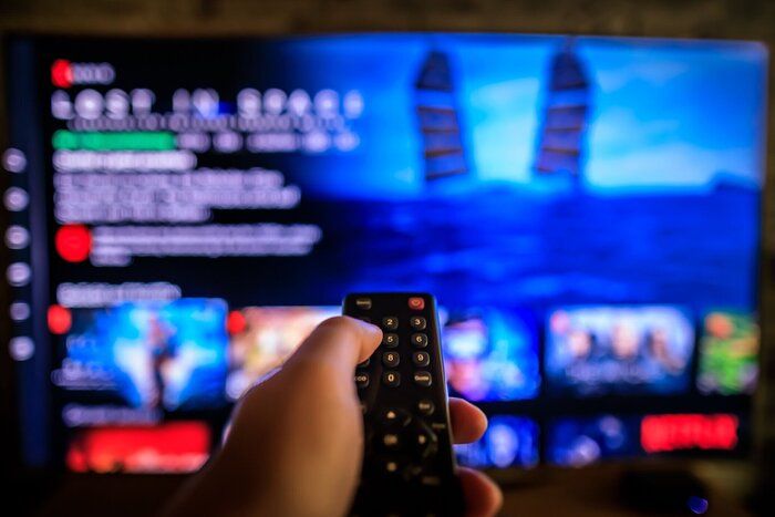 前景のテレビリモコン、ぼやけた背景のビデオオンデマンド画面