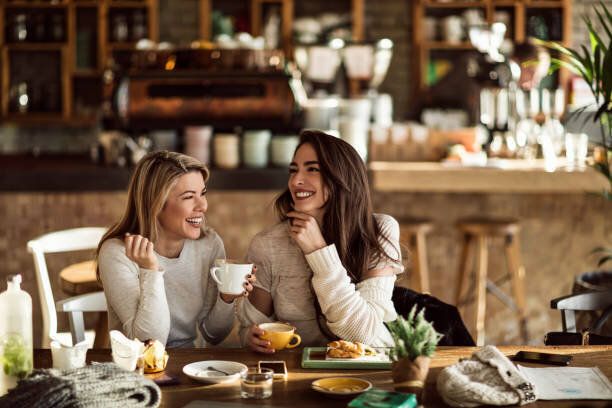 カフェでコーヒータイムを楽しんでいる2人の陽気な女性。