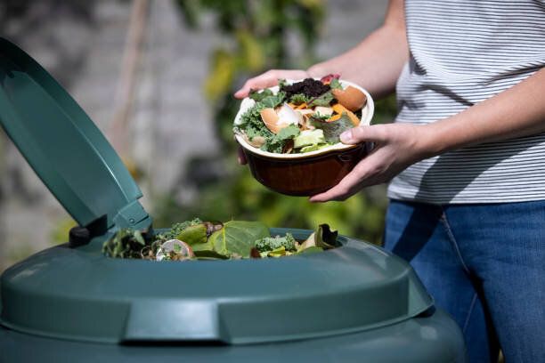 自宅で庭の堆肥に食品廃棄物を空にする女性のクローズアップ