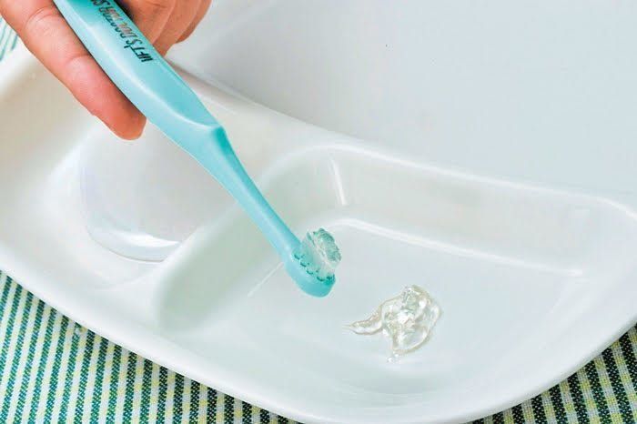 トレーの上に置かれた歯磨きペーストを歯ブラシにつける様子