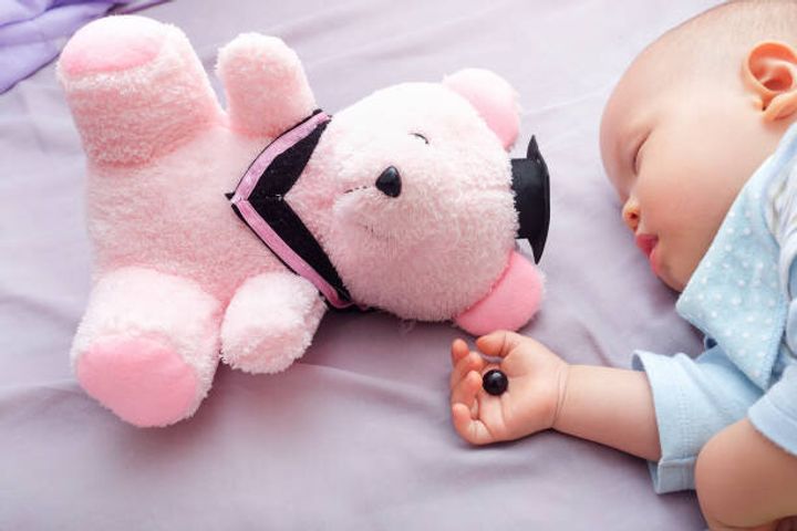 テディー ・ ベアの目は生後 10 ヶ月の赤ちゃんの手を睡眠で幼児がデタッチされた、子供の概念のための危険を窒息に注意