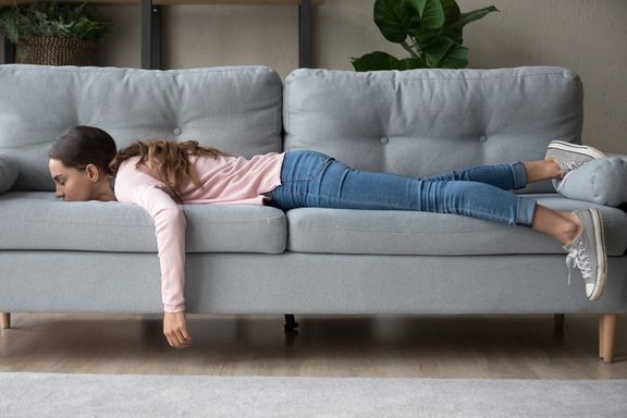 ソファに顔を埋めた横たわる若い女性は疲れを感じる
