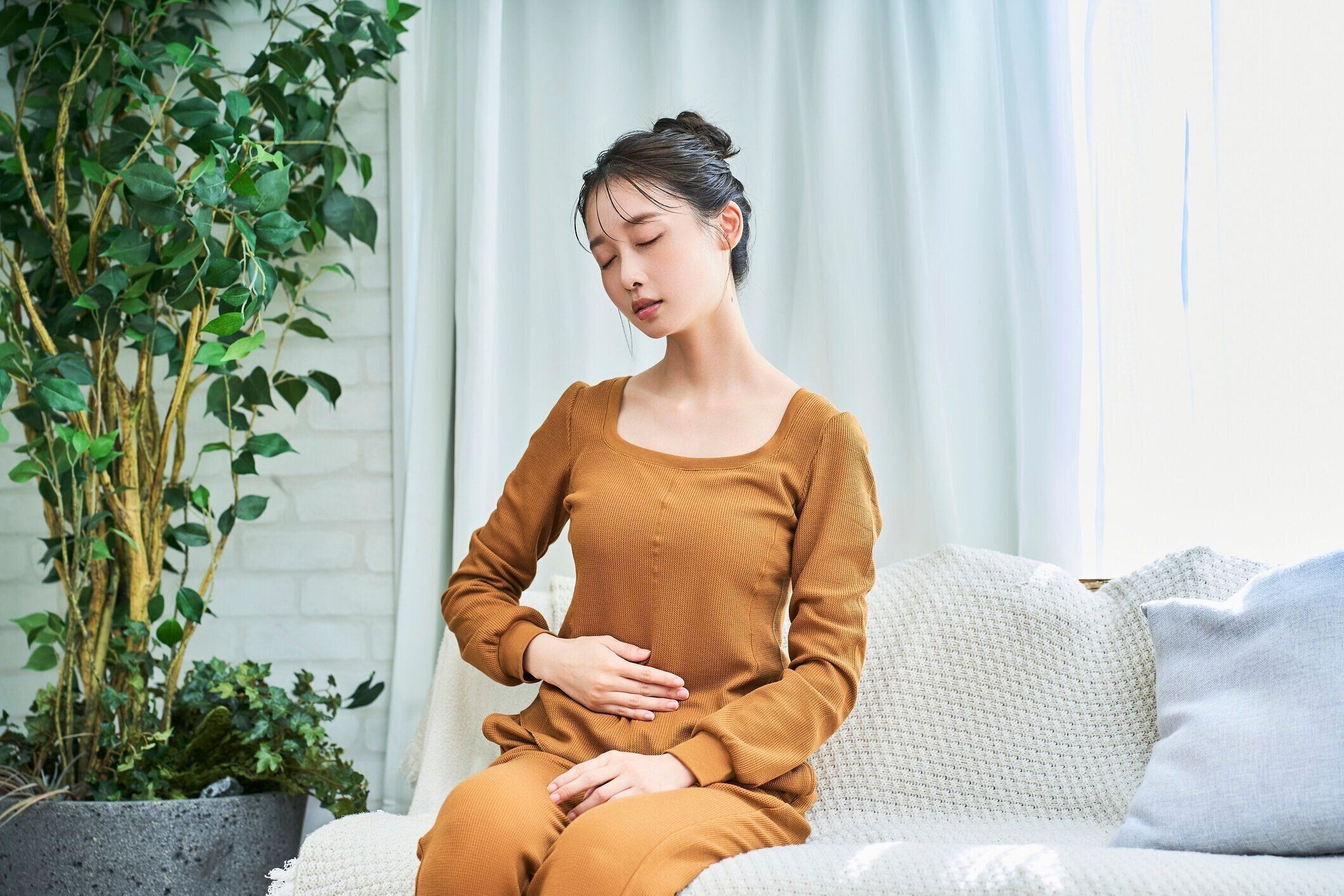 腹痛に苦しむ部屋着を着た若い女性
​