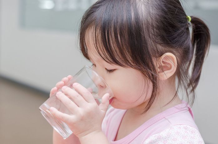 ガラスから水を飲む小さな女の子