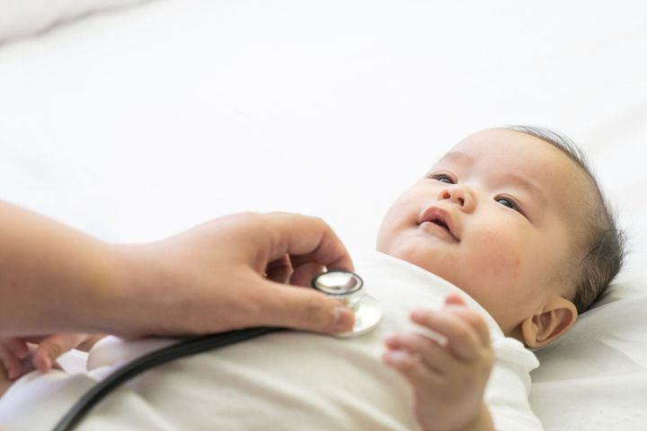 医師が検査アジアの新生児の聴診器の病院