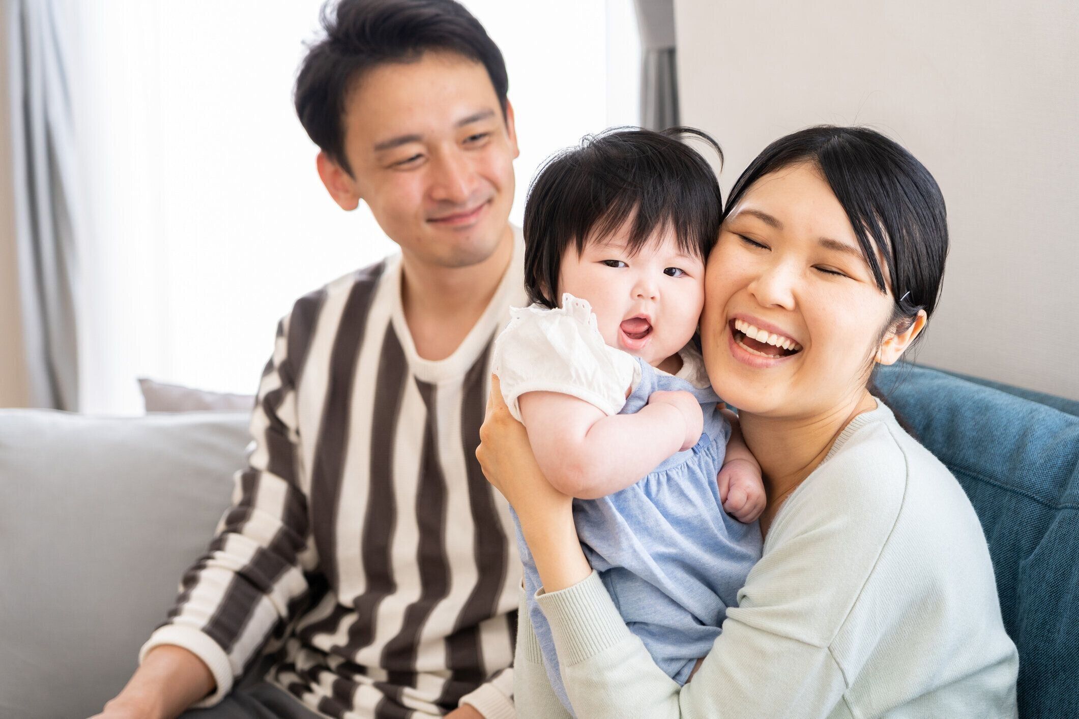 若いアジア家族のソファーでリラックス