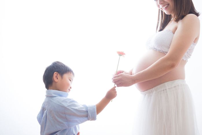 妊娠中の女性少年と花と遊ぶ