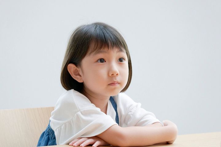 椅子の上で考えているアジアの女の子