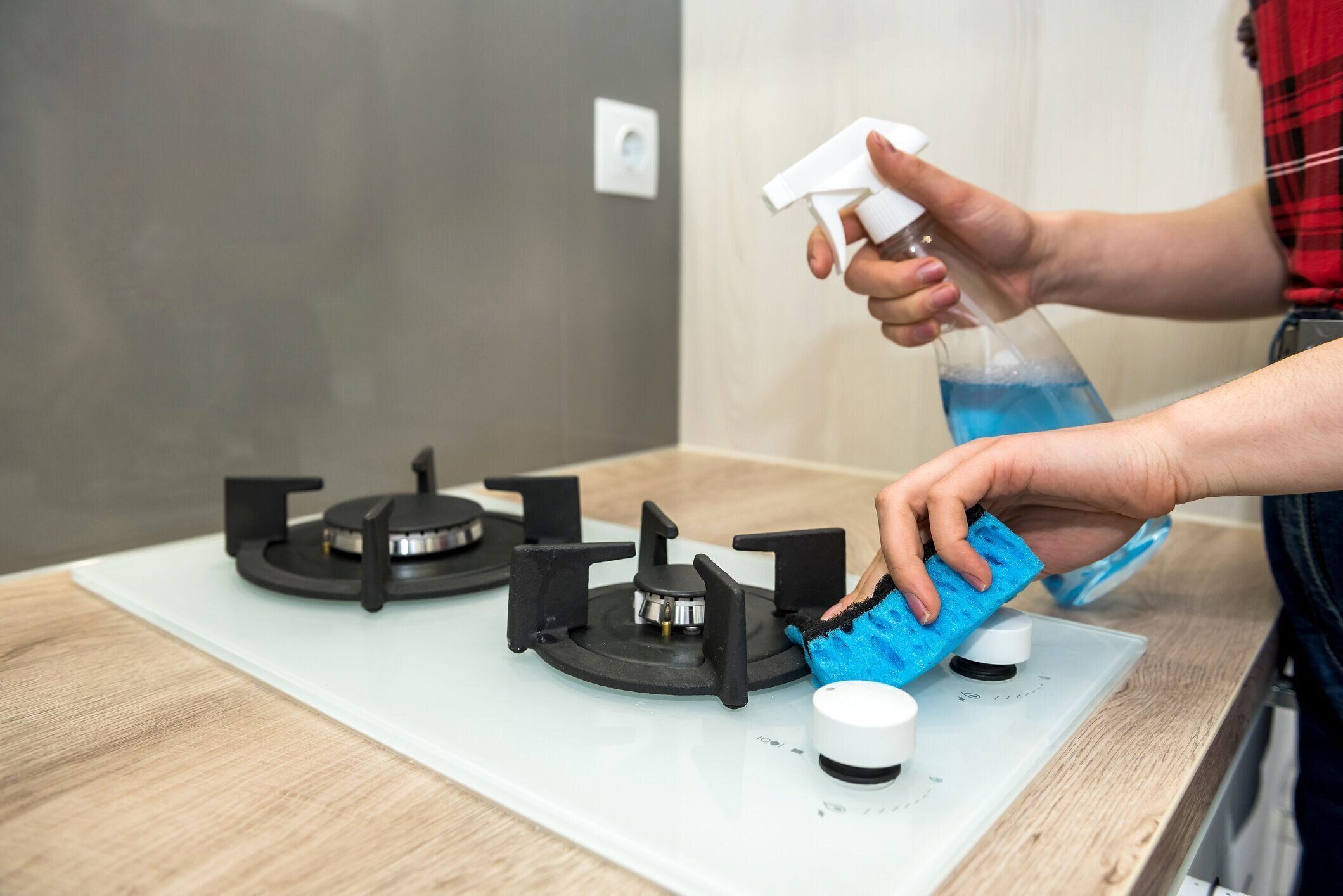 台所で洗剤でガスストーブを洗う主婦。ハウスクリーニング