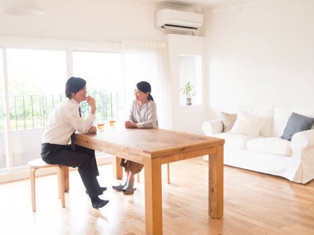 若いアジア家族のリビング ルームでの話