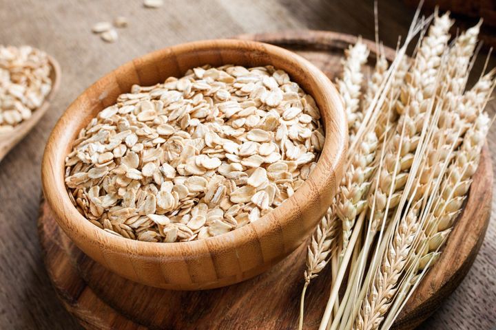 転がされたオートムギまたはオート麦フレーク、木製の背景に黄金の小麦の穂。