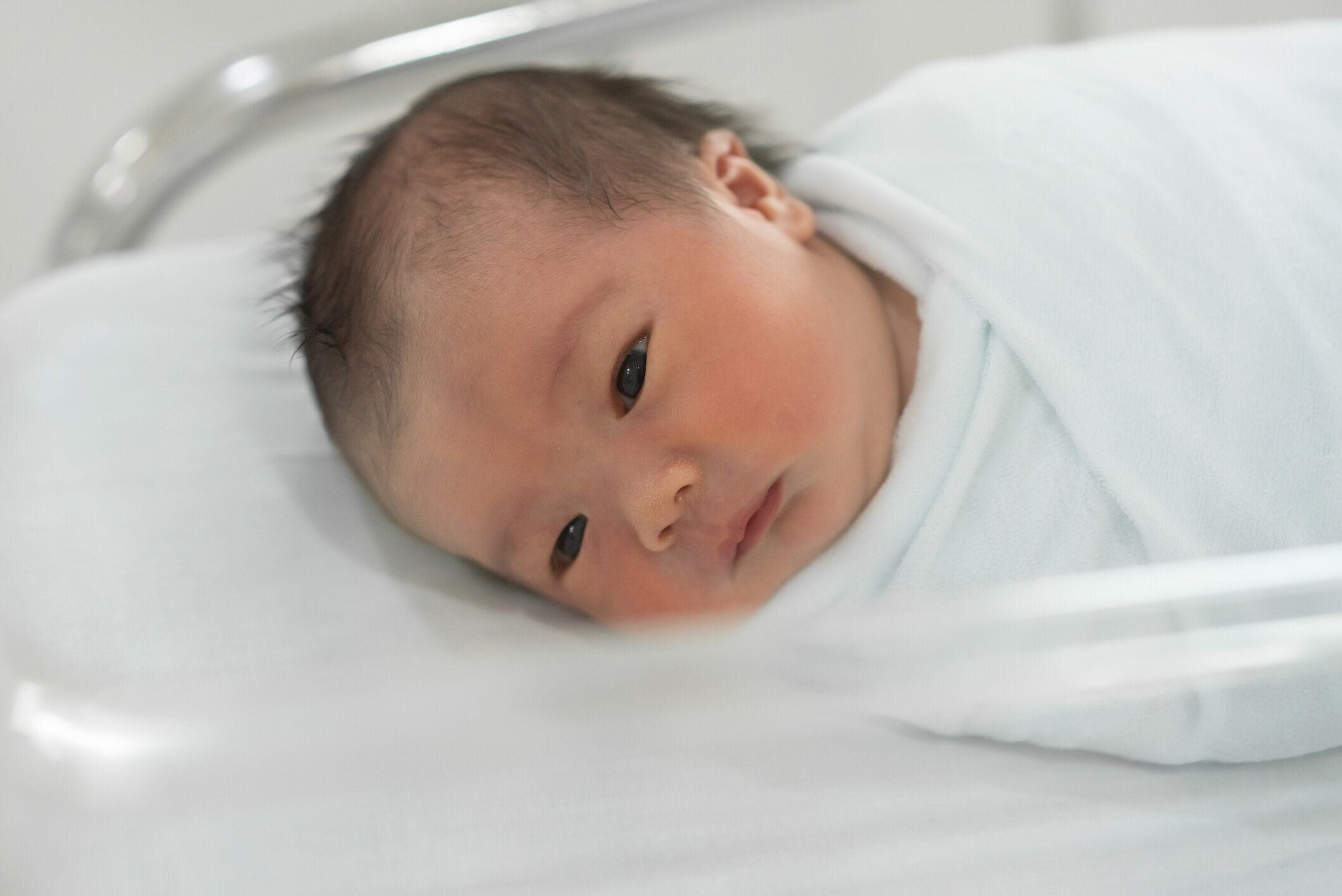 病院で白いベッドに横たわっているアジアの新生児。