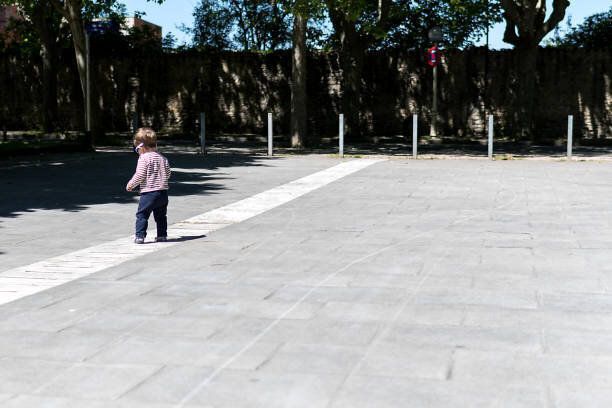 青いサングラスをかけて通りを歩いている1歳半の男の子