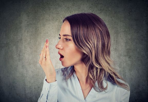 女性は手で彼女の息をチェックします。