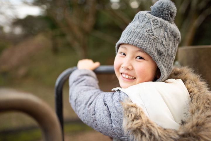 冬の公園で遊んでいる笑顔の女の子