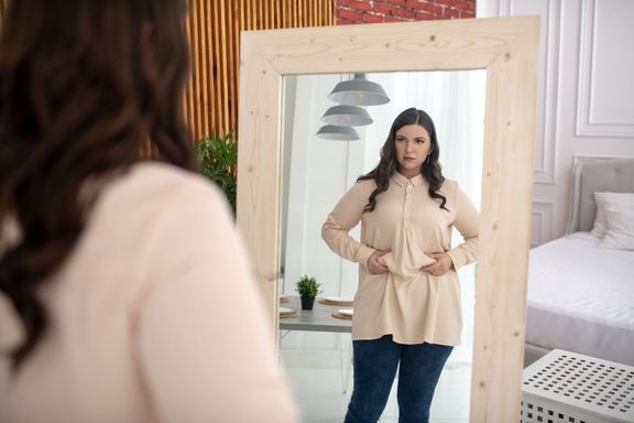 彼女の腹に触れるベージュのブラウスの若い女性