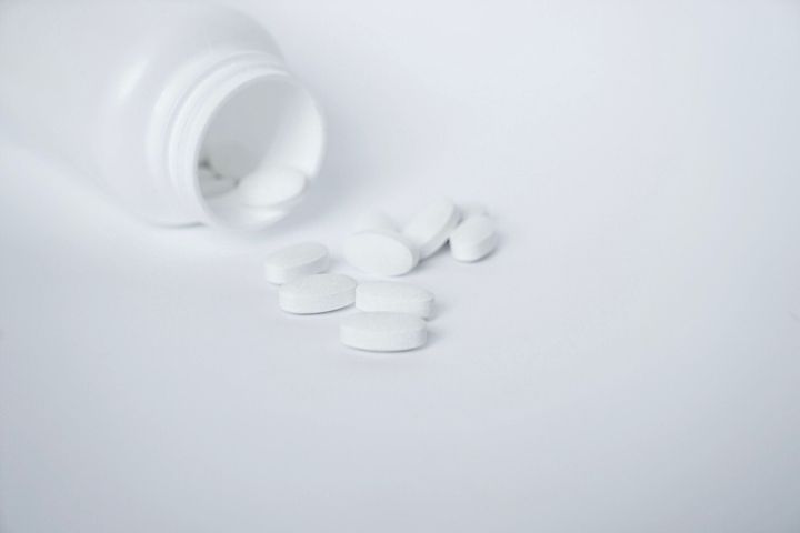白い背景の上のボトルの白い薬の丸薬