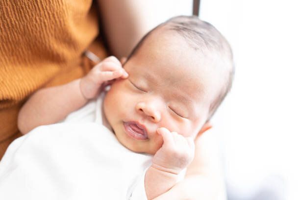 母親の腕の中で眠っている赤ちゃん